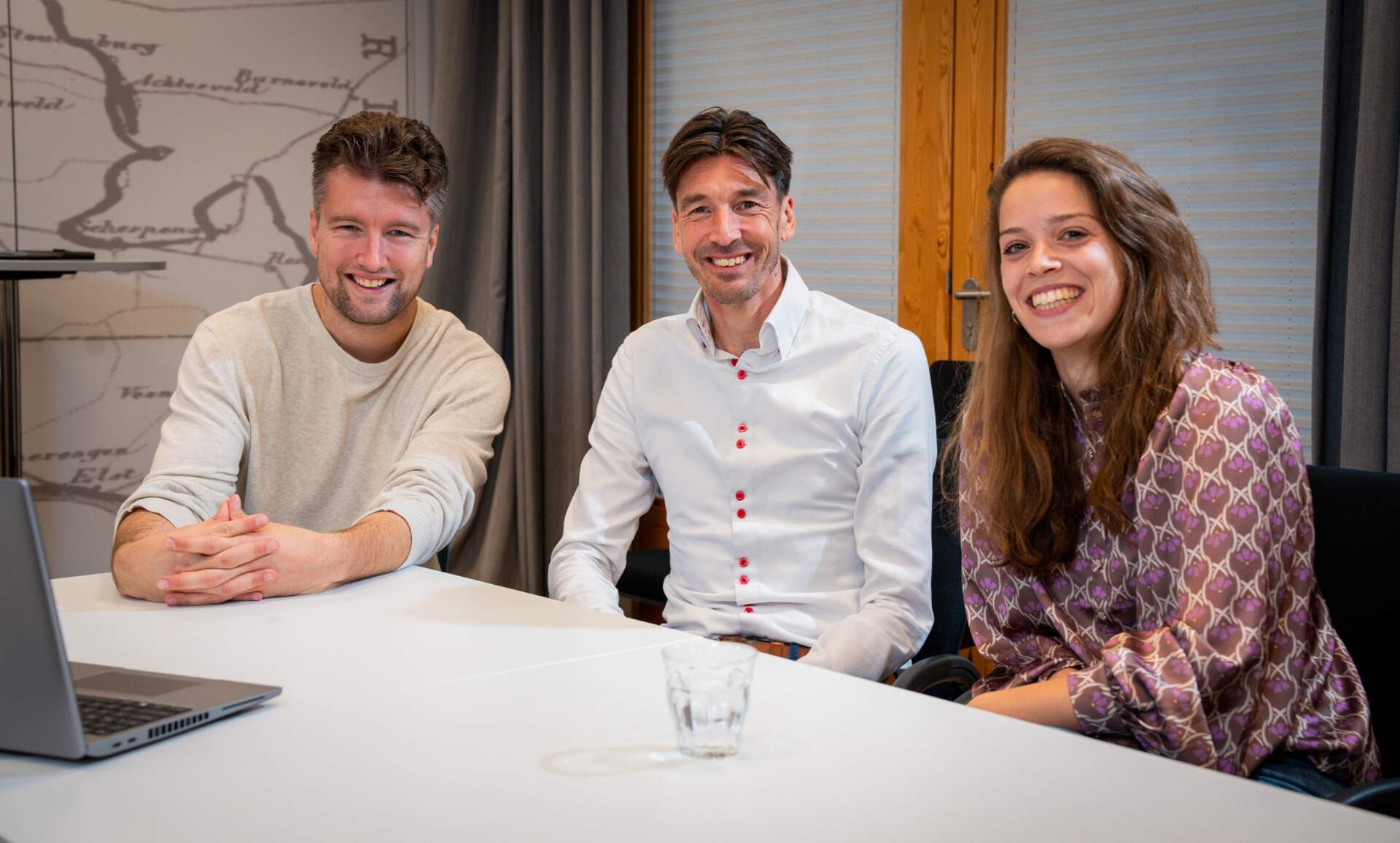 Drie collega's zitten naast elkaar en lachen