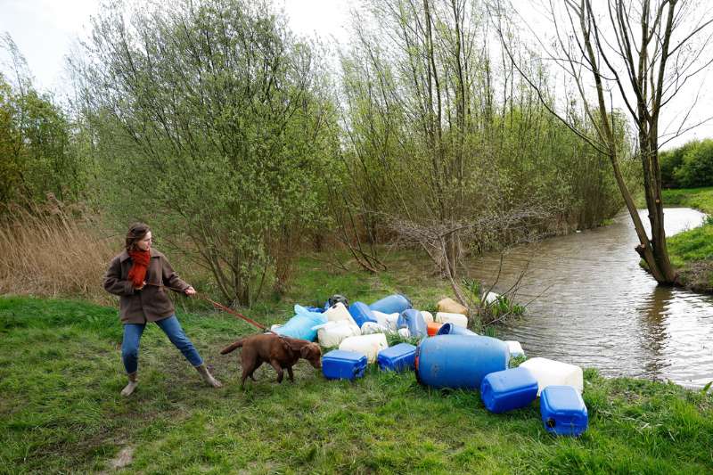 Gedumpte vaten en jerrycans langs een waterkant